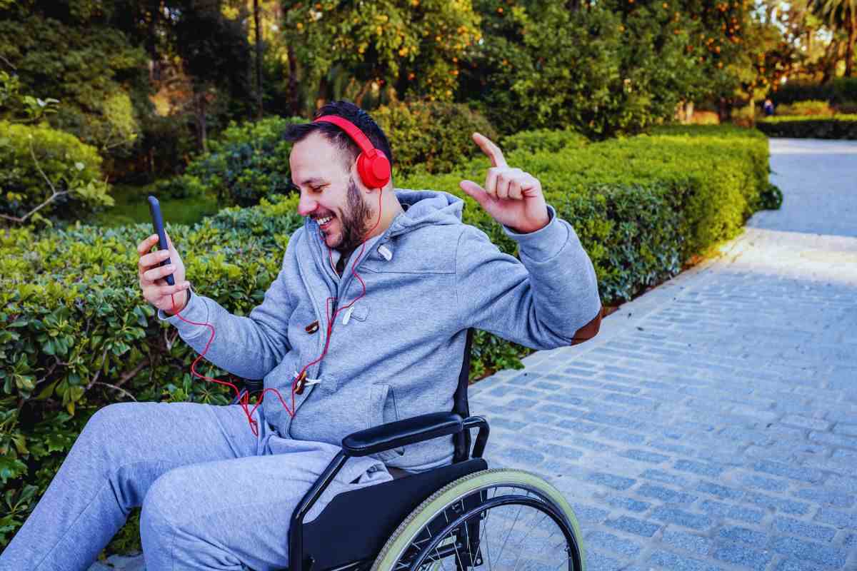 un ragazzo sulla sedia a rotelle con lo smartphone